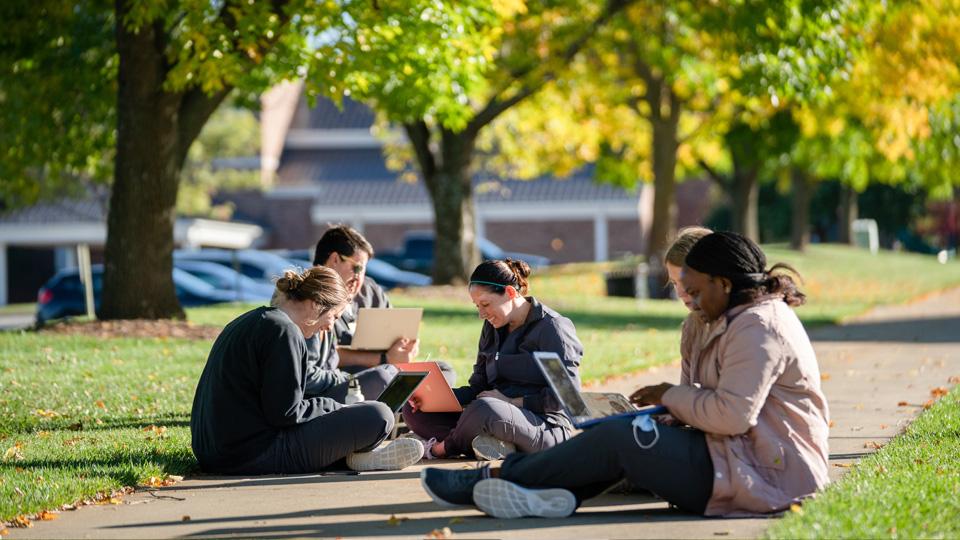 Students sitting on the sidewalk on the Campus Mall